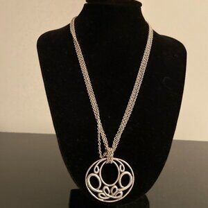 Silver tone necklace with circular knot pendant.